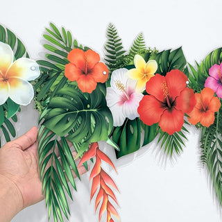 Tropical flower banner garland close-up with green leaves and orange, pink, and white flowers