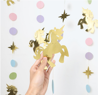 Close-up unicorn charm being attached to pastel bead hanging garland with gold accents