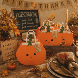Pumpkin-shaped fall party gift bags, orange with green tops and smiling faces, four pack