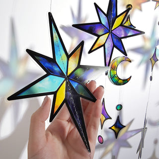 Hand holding star and moon hanging garland charm with iridescent plastic finish