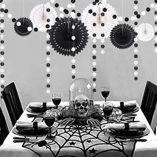 Black and white rosette and dot hanging garlands above a Halloween table setting