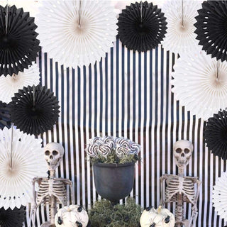 Black and white paper rosettes and dot garland discs arranged around a striped backdrop