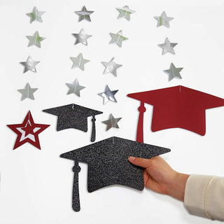 Graduation cap and star banner pieces held in hand: dark glitter mortarboards, burgundy caps