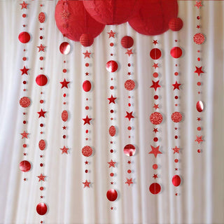 Red hanging star and circle garland streamer strands over white fabric backdrop