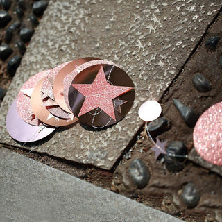 Close-up of glitter star and round ornaments on garland strings