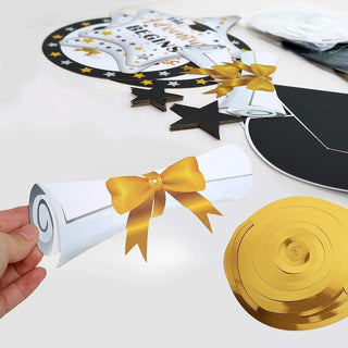 Gold and black graduation hanging swirls featuring paper Congrats Grad medallions, stars, and caps in close-up