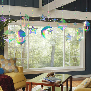 Iridescent hanging lantern garland with star, moon, and mosque silhouettes over window.