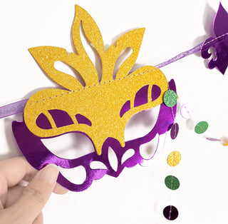 Glitter Mardi Gras mask decoration on purple ribbon with dangling bead garland